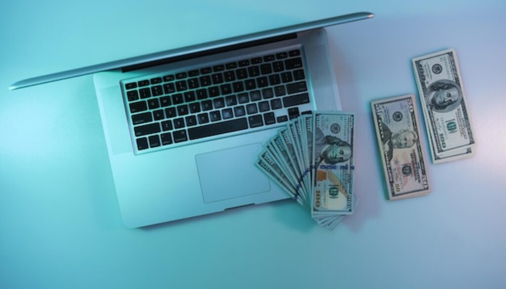 beautiful-silver-laptop-cash-dollars-banknote-color-light-table-background-work-night-concept-top-view_181667-25509