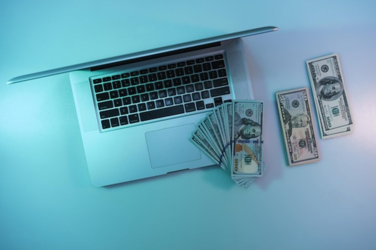 beautiful-silver-laptop-cash-dollars-banknote-color-light-table-background-work-night-concept-top-view_181667-25509