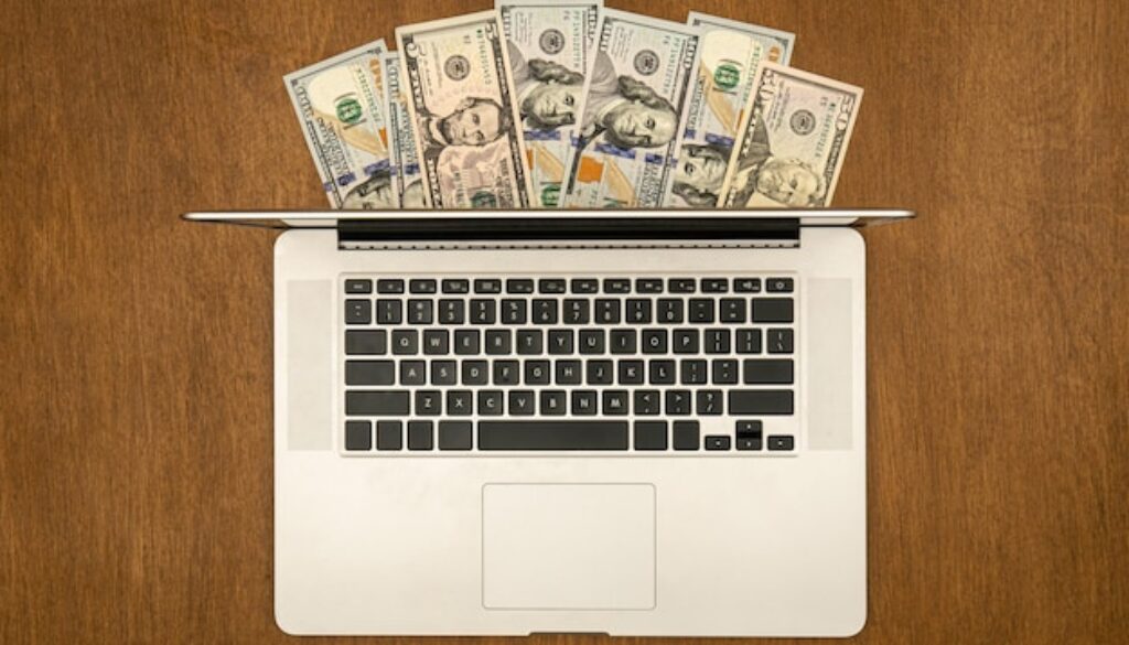 laptop-dollar-bills-wooden-background-flat-lay_169016-24683
